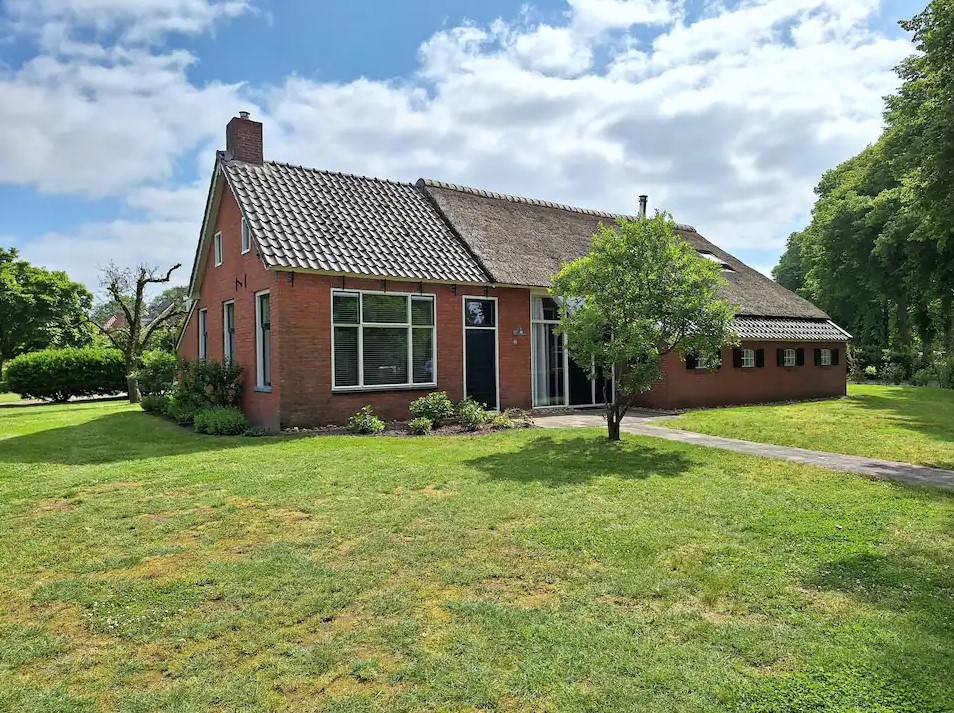 De woonboerderij in Zeijen met rieten dak, gezien vanaf het gazon